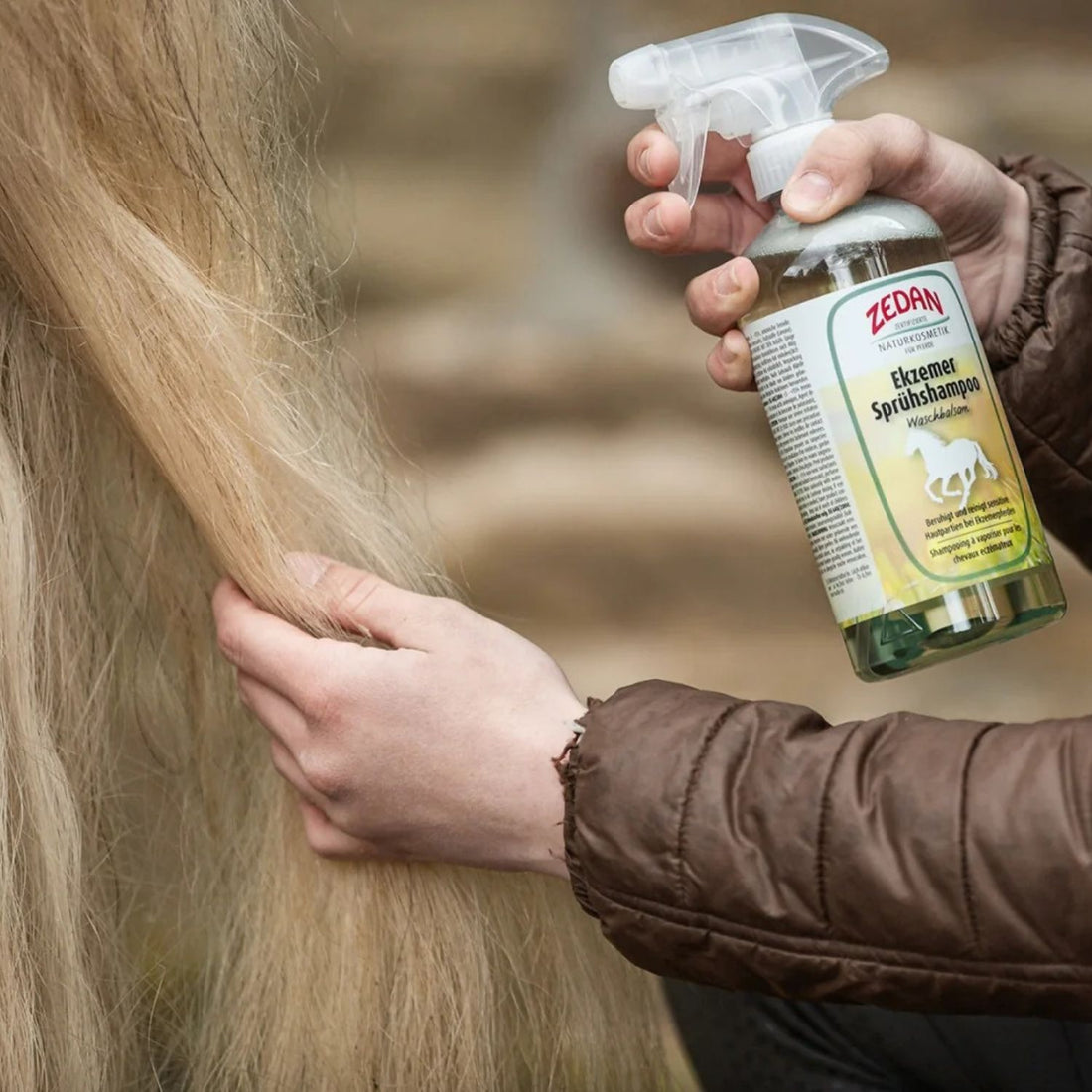 Pflege einer Pferdemähne mit Zedan Ekzemer-Sprühshampoo in der Hand.