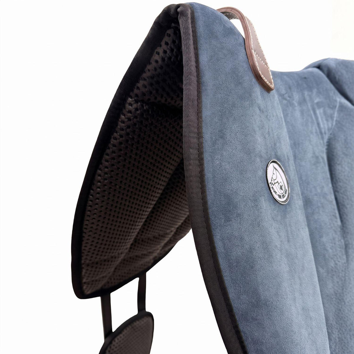 Die Detailaufnahme des blauen Brockamp Bareback Pad Reitpad Spezial zeigt das Reitkissen von vorne mit Blick auf die strukturierte, rutschfeste Anti-Slip-Unterseite aus Neopren im Übergang zur feinen Wildleder-Oberfläche. Erkennbar sind das runde Brockamp-Logo-Emblem, der braune Ledergriff mit Kontrastnaht und die robuste Kantenverarbeitung für optimalen Halt beim Reiten ohne Sattel.