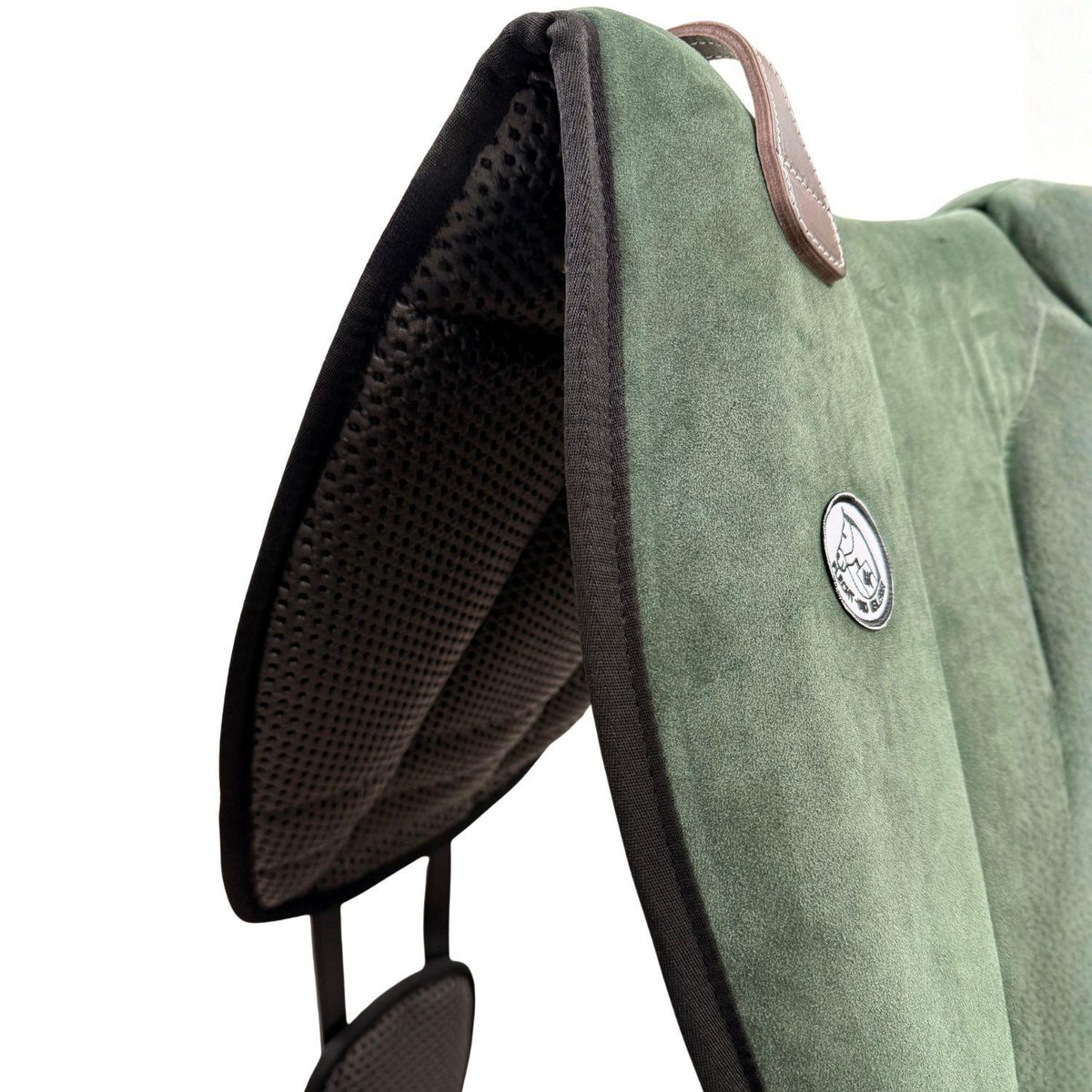 Die Detailaufnahme des grünen Brockamp Bareback Pad Reitpad Spezial zeigt das Reitkissen von vorne mit Blick auf die strukturierte, rutschfeste Anti-Slip-Unterseite aus Neopren im Übergang zur feinen Wildleder-Oberfläche. Erkennbar sind das runde Brockamp-Logo-Emblem, der braune Ledergriff mit Kontrastnaht und die robuste Kantenverarbeitung für optimalen Halt beim Reiten ohne Sattel.