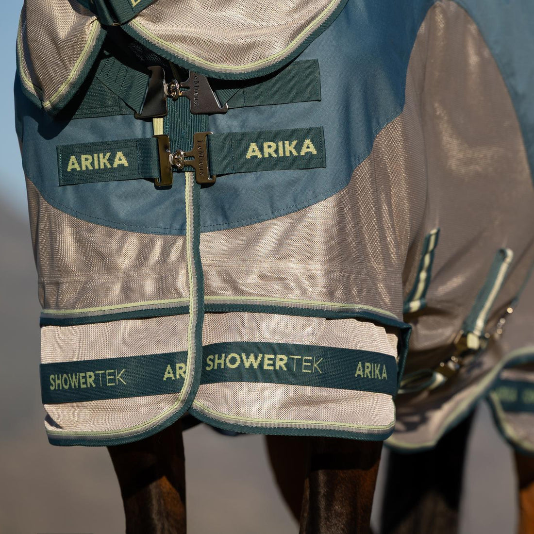 Die Detailaufnahme zeigt den innovativen, um 45 Grad abgewinkelten Brustverschluss mit stabilen T-Stegen der LeMieux Arika Camo Shower-Tek Fliegendecke, der sich auf der Brust selbst ausrichtet, die Schultern entlastet und unangenehmes Scheuern verhindert.