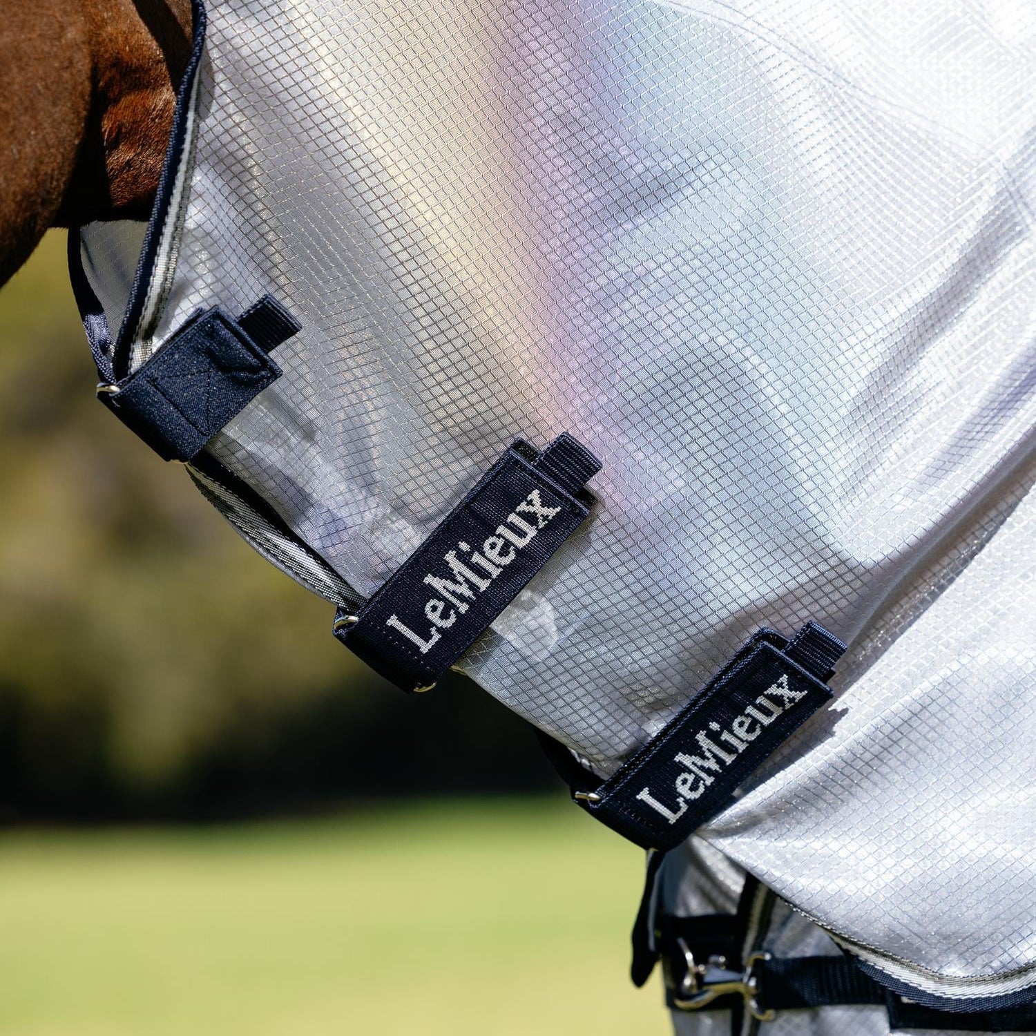 Nahaufnahme der robusten Klettverschlüsse am abnehmbaren Halsteil der LeMieux Fliegendecke kudos Aeroguard. Das strapazierfähige Ripshield-Mesh aus Nylon und Monofilament-Polyester schimmert im Sonnenlicht perlmuttartig. Das Halsteil ermöglicht ein pferdegerechtes Deckenmanagement, das sich flexibel an das tägliche Insektenaufkommen anpassen lässt.