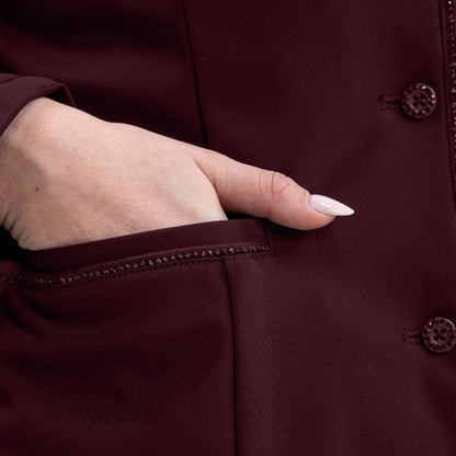 Detailaufnahme der rechten Einschubtasche des Harcour Damen Reitjackets Oria in Aubergine. Eine Turnierreiterin schiebt ihre Handspitze in die praktische Tasche, welche edel mit funkelnder Glitzerlitze verziert ist. Durch diese sich wiederholenden Glitzer- und Designelemente entsteht ein harmonisches Gesamtbild der exklusiven Harcour Turnierbekleidung. Ein funktionales und zugleich stilvolles Turniersakko für Frauen, die auf dem Turnierplatz Wert auf durchdachte Details legen.