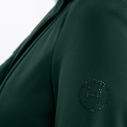 Detailansicht des linken Ärmels des Harcour Oria Jungle Damen Turnierjackets mit dem runden, durch Strasssteine und Glitzer verzierten Harcour-Logo, passend zur dunkelgrünen Grundfarbe des Turniersakkos. Raffiniertes Glitzer-Detail in dezenter Eleganz.