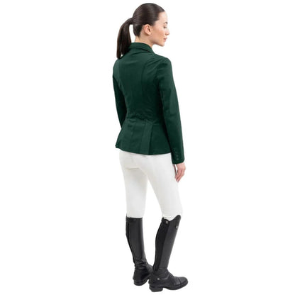 Rückansicht einer Reiterin im Harcour Damen Turnierjacket Oria. Die luxuriöse Farbe Jungle, ein dunkler Grünton inspiriert durch die Farben des Dschungels, perfekt mit weißer Turnierkleidung kombinierbar.. An der Taille funkelt der edle Harcour Glitzerschriftzug. Das elegante Schößchen, oft auch Reitrock genannt, bietet dank zwei seitlicher Schlitze höchste Flexibilität und Bewegungsfreiheit im Sattel. Ein exklusives Reitsakko, das im Turniersport durch edles Design perfekt in Szene gesetzt wird.