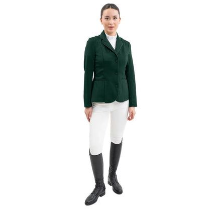 Eine Turnierreiterin präsentiert ein komplettes Harcour Turnieroutfit. Sie trägt das Damen Turnierjacket Oria in Jungle, kombiniert mit weißer Turnierreithose und dem Harcour Turniershirt Shine mit weißem Latz. Dieses edle Reitsakko setzt optische Highlights und bietet maximale Sicherheit: Es ist kompatibel mit dem Harcour Ouraye HIT AIR Airbag und allen Airbagwesten, die unter der Turnierkleidung getragen werden. Ein elegantes und sicheres Reitoutfit für den anspruchsvollen Turniersport.