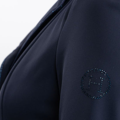 Detailansicht des linken Ärmels des Harcour Oria Navy Damen Turnierjackets mit dem runden, durch Strasssteine und Glitzer verzierten Harcour-Logo, passend zur dunkelblauen Grundfarbe des Turniersakkos. Raffiniertes Glitzer-Detail in dezenter Eleganz.