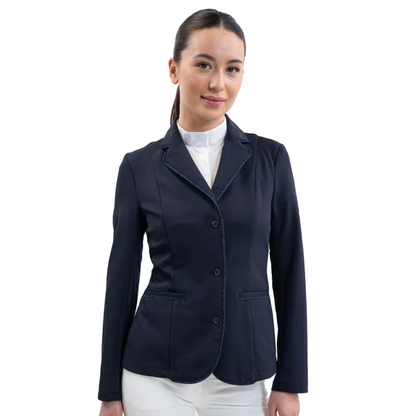 Eine Turnierreiterin präsentiert das feminine Harcour Damen Turnierjacket Oria in Navy, einem luxuriösen, dunkelblauen Farbton. Das figurbetonte Reitsakko mit hochelastischem Harcour-Riders-Stretch wird mit weißem Harcour Turniershirt und weißer Turnierreithose kombiniert. Die rahmende Glitzerlitze von Kragen bis Saum, betonte vordere Einschubtaschen sowie mit Kristallsteinen verzierte Knöpfe an Ärmeln und Verschluss machen die Reitjacke zum Blickfang.