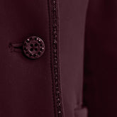 Detailaufnahme der Vorderseite mit dem edlen Knopfverschluss der Harcour Damen Turnierreitjacke Oria in Aubergine. Das Bild zeigt das harmonische Zusammenspiel der mit Kristallsteinen veredelten Knöpfe und der funkelnden Glitzerlitze, die das Reitsakko vom Kragen bis zum Saum rahmt. Diese hochwertige Verarbeitung der sichtbaren Knöpfe über dem Double-Closure-System ist eine Besonderheit der Turnierbekleidung für Reiterinnen, die ein exklusives und individuelles Turnieroutfit suchen.