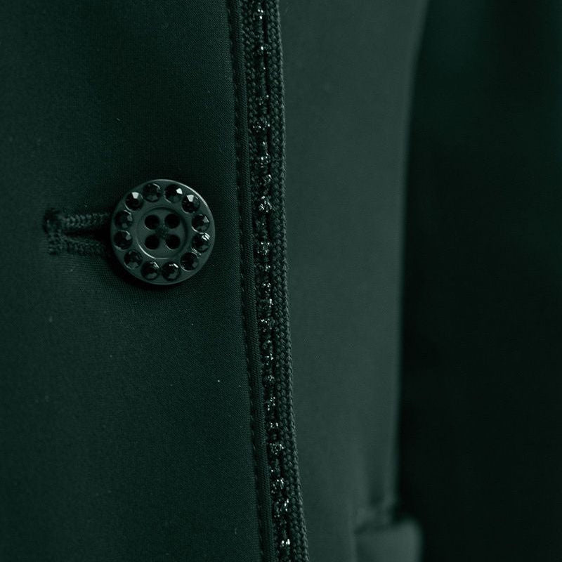 Detailaufnahme der Vorderseite mit dem edlen Knopfverschluss der Harcour Damen Turnierreitjacke Oria in Jungle. Das Bild zeigt das harmonische Zusammenspiel der mit Kristallsteinen veredelten Knöpfe und der funkelnden Glitzerlitze, die das Reitsakko vom Kragen bis zum Saum rahmt. Diese hochwertige Verarbeitung der sichtbaren Knöpfe über dem Double-Closure-System ist eine Besonderheit der Turnierbekleidung für Reiterinnen, die ein exklusives und individuelles Turnieroutfit suchen.