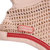 Harcour Fliegenohren Fredy Coquillage Shell in gehäkelter Häkeloptik. Sichtbar sind das dezente Einfassband, die korallefarbene Litze und das seitliche Harcour-Logo-Batch. Handgefertigter Fliegenschutz für Pony und Warmblut.