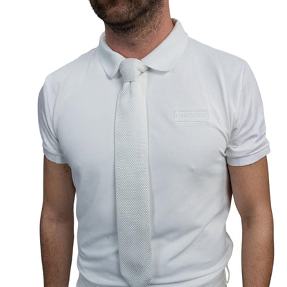 Detailansicht der weißen Harcour Herren Turnierkrawatte Corbi, perfekt kombiniert mit einem weißen Turnierpolohemd. Die vorgebundene Krawatte sitzt dank Easy-Close-System auch ohne Sakko präzise am Polokragen. Sportlich-elegante Turnierkleidung für warme Turniertage im Dressur- und Springsport.