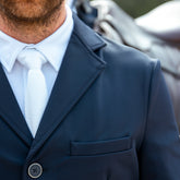 Weiße Harcour Herren Turnierkrawatte Corbi im edlen Kontrast unter einem navyblauen Harcour Turniersakko. Die markante Waffelpique-Struktur unterstreicht die perfekte Turnierkleidung für Herren. Stilvolle Kombination aus Accessoire und Reitsakko für den professionellen Reitsport.