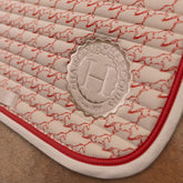 Detail der Harcour Schabracke Karembar Jump Shell Grapefruit: Horizontale Steppung, helles Einfassband in Beige und korallfarbene Litze passend zum Pferdeprint. Das runde Harcour Logo Batch in Shell sorgt für einen stylischen Auftritt im Spring-, Dressur- oder Ponysattel.