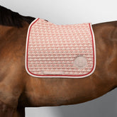 Harcour Dressurschabracke Karembar in Jump Shell Beige mit Grapefruit-Kontrast auf einem braunen Pferd. Zu sehen ist der anatomische Schnitt am Widerrist, die horizontale Steppung und die korallefarbene Litze. Die warme Farbe Shell harmoniert perfekt mit dem braunen Kurzhaar und schwarzem Langhaar des Pferdes. Geeignet für langes Sattelblatt.