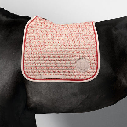 Edle Harcour Karembar Dressur Schabracke Jump Shell Grapefruit auf einem schwarzen Rappen. Das beige Außenmaterial (Shell) bildet einen luxuriösen Kontrast zum schwarzen Kurzhaar und Langhaar. Der anatomische Schnitt und die korallefarbene (Grapefruit) Litze betonen die Eleganz auf dem dunklen Pferd. Ideal für Dressursättel.