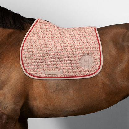 Harcour Springschabracke Karembar Jump in Shell Beige auf einem braunen Pferd. Die korallefarbene Grapefruit-Litze setzt sportliche Akzente zum braunen Kurzhaar. Anatomischer Schnitt für Widerristfreiheit, ideal für Springtraining und Springsättel. Farbharmonie pur.