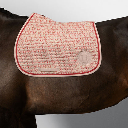 Harcour Karembar Springschabracke in Jump Shell Grapefruit auf dunkelbraunem Pferd. Die korallefarbene Litze kontrastiert edel zum dunklen Kurzhaar. Anatomisch geformt für moderne Springsättel und tägliches Training. Klare Linien durch horizontale Steppung.