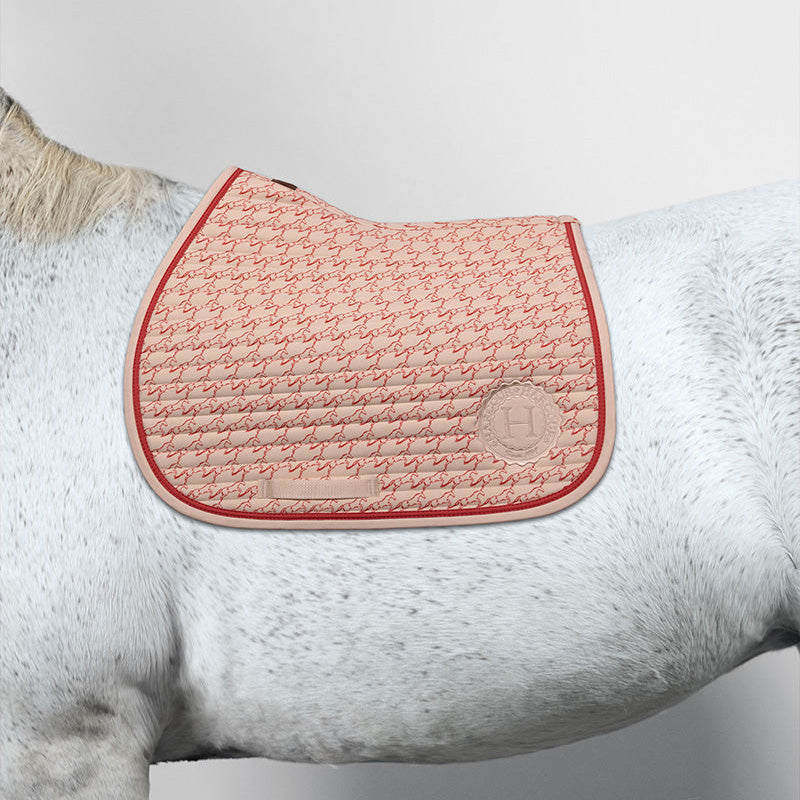 Harcour Springschabracke Karembar Jump Shell Beige und Koralle auf weißem Schimmel. Frisches Design mit graphischem Pferdeprint für moderne Springsättel. Anatomische Form für maximale Freiheit im Springen. Ein echter Blickfang für tägliche Reiteinheiten.