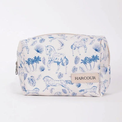 Die frontale Ansicht der Harcour Kulturtasche Pam zeigt das kompakte, grifflose Design, das sich perfekt als platzsparende Schminktasche, Make-up Bag oder Organizer für Turnierzubehör eignet. Ohne störende Henkel lässt sich die weiße Tasche mit dem blauen Pferdeprint-Motiv mühelos in Koffern, Handtaschen oder Putzboxen verstauen und bietet vielseitige Nutzungsmöglichkeiten für persönliche Kleinigkeiten im Stallalltag