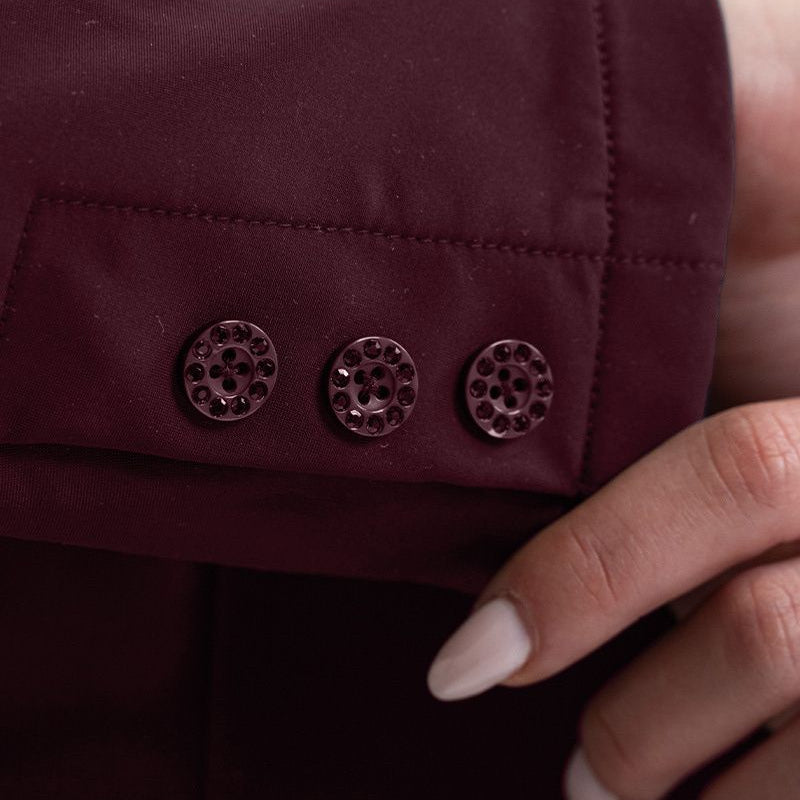 Detailbild der drei Knöpfe am rechten Ärmel des Harcour Turnierjackets Oria in Aubergine. Die eleganten Knöpfe sind, genau wie der Knopfverschluss, mit gleichfarbigen, dunkelroten Kristallsteinen besetzt und glitzern bei jeder Bewegung im Sonnenlicht. Diese edlen Ton-in-Ton Strasssteine runden das besondere Design des Reitsakkos perfekt ab. Ein luxuriöses Detail für modische Turnierreiterinnen, die auf der Suche nach außergewöhnlicher und hochwertiger Turnierbekleidung mit Strass sind.