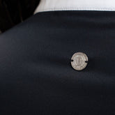 Die Rückansicht des Harcour-Turniershirts Shine schwarz mit dem dezenten, runden, silbernen Logo auf dem elastischen Stretchmaterial für optimale Bewegungsfreiheit. Der darüber liegende Stehkragen ist kontrastfarbig in Weiß abgesetzt. 