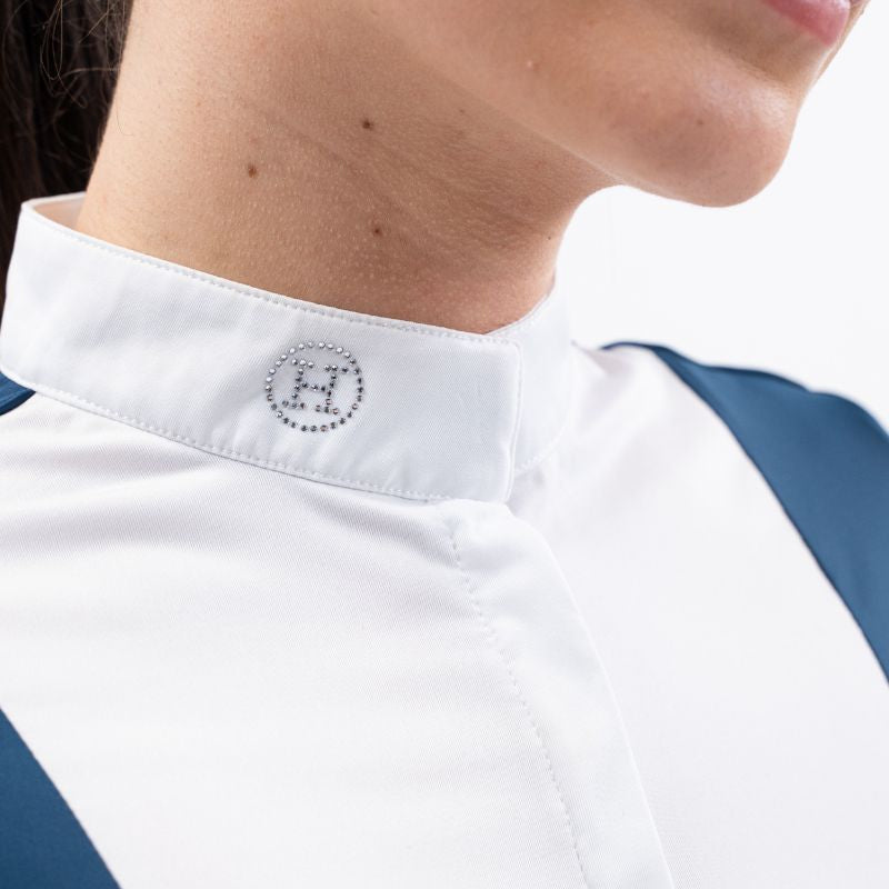 etailansicht des Stehkragens am Harcour Turniershirt Shine Blue Logoon mit dem funkelnden Kristall-Glitzerlogo auf der rechten Halsseite, der elegant unter einem Turnierjacket oder Reitfrack hervorsteht und die innovative Funktion des Magnetverschlusses für ein einfaches Schließen andeutet.