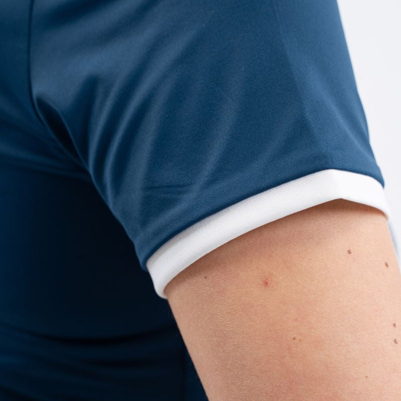 Eine Detailaufnahme des Harcour Turniershirts Shine in Blue Lagoon zeigt den in Weiß abgesetzten Kurzarmabschluss, der einen verspielten Farbkontrast zur petrolfarbenen Hauptfarbe bildet und das Oberteil auch ohne Turnierjacket – etwa bei Marscherleichterung, im sommerlichen Reittraining oder als sportlich-elegantes Outfit im Büro – zu einem stilvollen Hingucker macht.