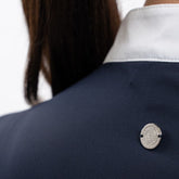 Die Rückansicht des Harcour Turniershirts Shine Navy mit dem dezenten, runden, silbernen Logo auf dem elastischen Stretchmaterial für optimale Bewegungsfreiheit. Der darüber liegende Stehkragen ist kontrastfarbig in Weiß abgesetzt. 