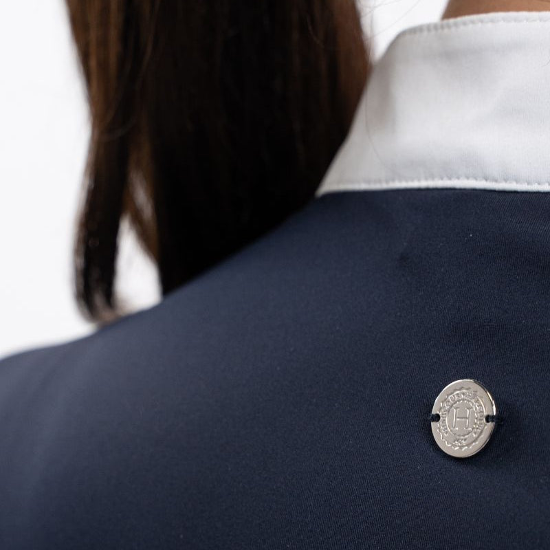 Die Rückansicht des Harcour Turniershirts Shine Navy mit dem dezenten, runden, silbernen Logo auf dem elastischen Stretchmaterial für optimale Bewegungsfreiheit. Der darüber liegende Stehkragen ist kontrastfarbig in Weiß abgesetzt. 