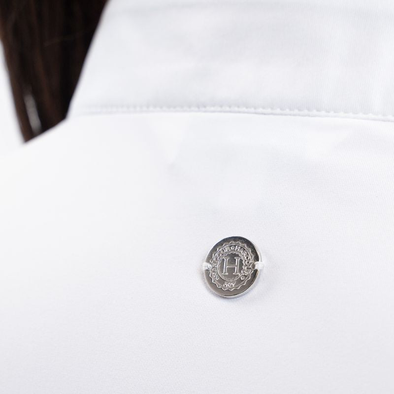 Die Rückansicht des Harcour Turniershirts Shine White mit dem dezenten, runden, silbernen Logo auf dem elastischen Stretchmaterial für optimale Bewegungsfreiheit. Der darüber liegende Stehkragen in Weiß ragt aus dem Turnierjacket heraus und macht ein Plastron überflüssig. 