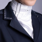 Weißes Harry’s Horse Plastron Diamond, getragen über einem Turniershirt und perfekt eingepasst in den V-Ausschnitt eines blauen Turnierjackets. Die hellen Glitzersteine am Kragen funkeln im Sonnenlicht, während das vorgebundene Plastron im Nacken per Klettverschluss einfach geschlossen wird.
