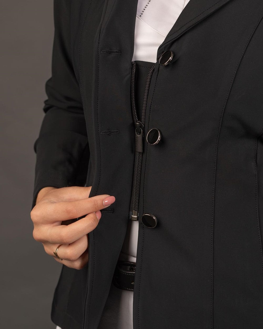 Die Detailaufnahme der innovativen Turnierjacke zeigt das clevere Double-Closure-System mit drei geöffneten Frontknöpfen und dem darunterliegend sicher geschlossenen Reißverschluss, der ein Aufklaffen verhindert.