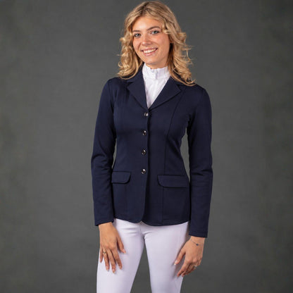 Reiterin im modernen dunkelblauen Harry’s Horse Turnierjacket Competition kombiniert mit weißer Turnierreithose und Turniershirt. Das Tragefoto zeigt die feminine, taillierte Passform der eleganten Turnierjacke sowie die 4-Knopf-Leiste und Klapptaschen im kompletten Turnieroutfit.