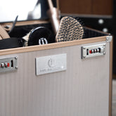 Nahaufnahme der Imperial Riding Putzbox IRHShiny Taupe Herringbone. Die Detailansicht zeigt das silberne Imperial Riding Frontlogo, das beige Fischgrätmuster mit Chevron-Struktur sowie die Zahlenschlösser der Schnappverschlüsse im roségoldenen Rahmen.