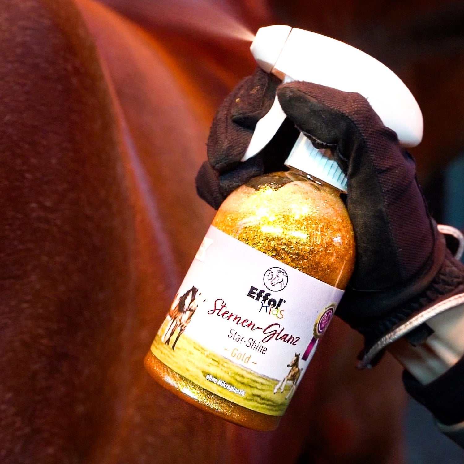 Das goldene Glitzerspray Effol Kids Sternen-Glanz wird hier direkt auf das Pferdefell gesprüht, um sofortigen, fruchtig duftenden Glanz für den besonderen Auftritt zu erzeugen.