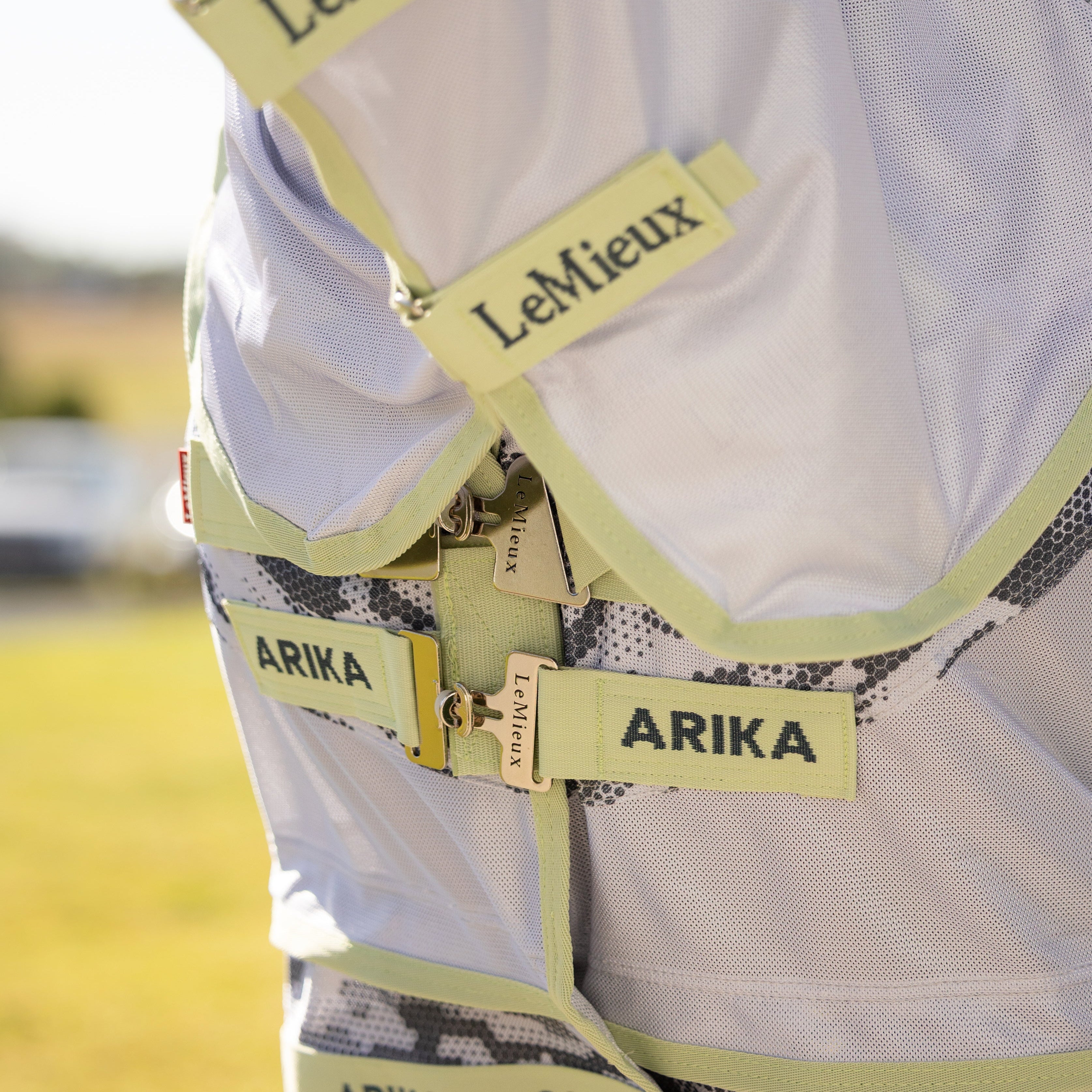 Die Nahaufnahme zeigt den innovativen Arika-Brustverschluss der LeMieux Fliegendecke mit seinen um 45 Grad abgewinkelten T-Stegen in der Kontrastfarbe Macaron, die für eine gleichmäßige Druckverteilung sorgen, sowie die stabilen Klettverschlüsse des passenden, abnehmbaren Halsteils.