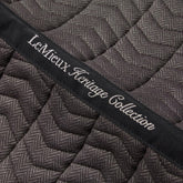 Detailaufnahme der LeMieux Heritage Dressurschabracke in Cocoa: Besticktes Topband der LeMieux Heritage Collection auf feiner Chevron-Steppung im braunen Fischgrätmuster. Das Topband verläuft mittig über die gesamte Rückenlinie. Die Bestickung dient der Kennzeichnung der Schabracke im Regal oder Sattelschrank.