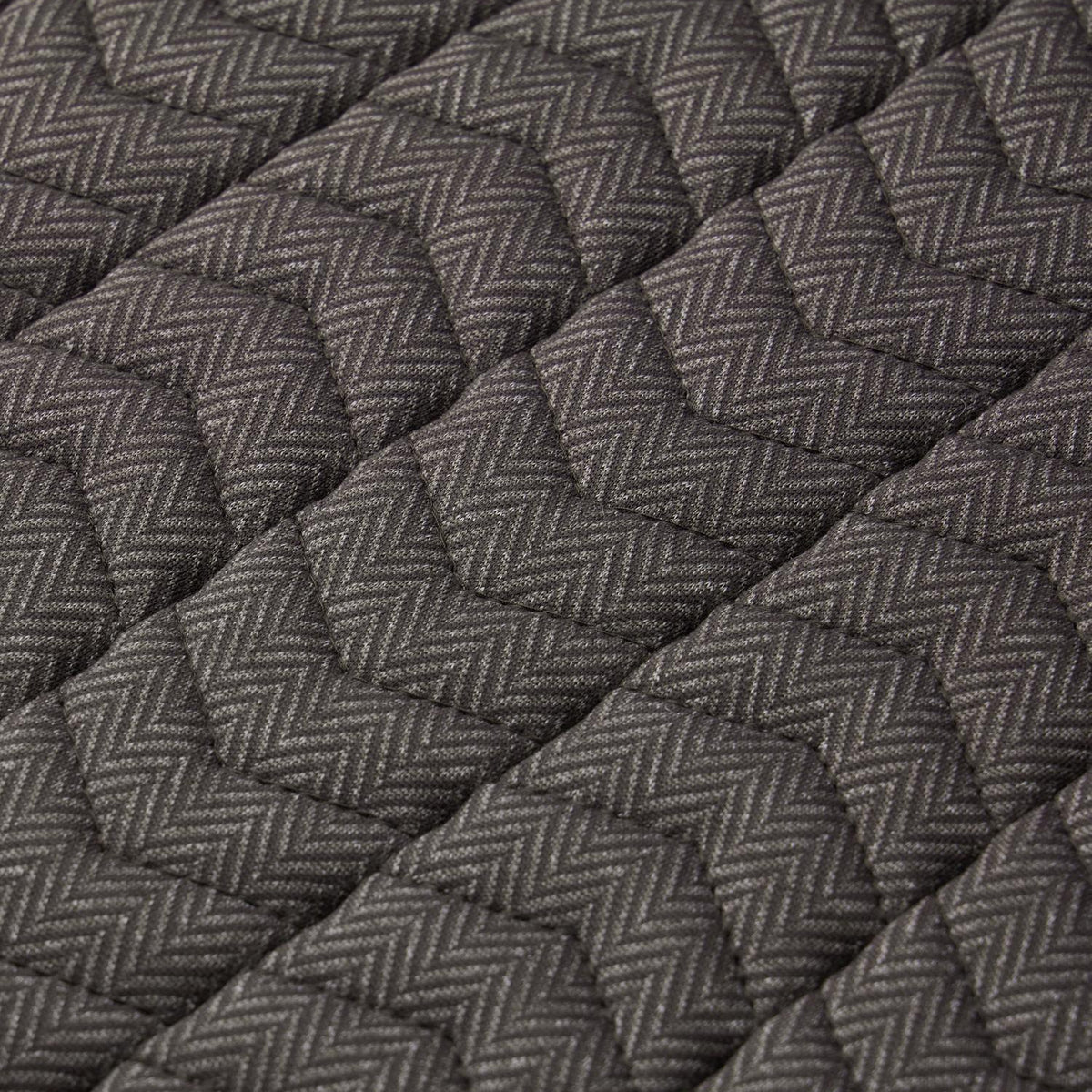 Nahaufnahme der LeMieux Heritage Dressurschabracke Herringbone in Cocoa: Detailansicht der präzisen Chevron-Steppung über dem gewebten Fischgrätmuster im warmen Braunton für eine elegante Optik und formstabile, flache Auflage am Pferderücken.