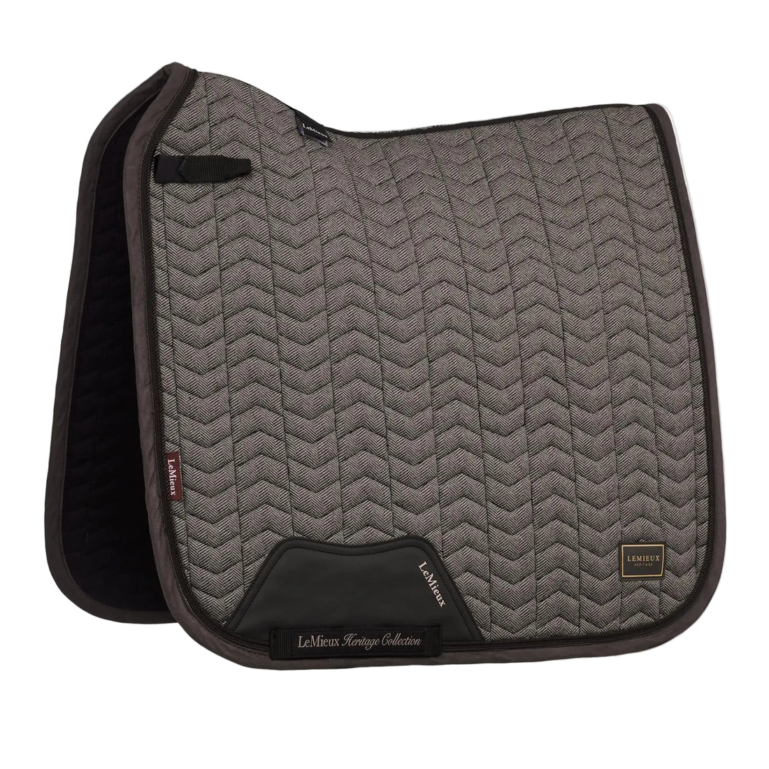 Die braune LeMieux Heritage Dressurschabracke Herringbone Dressage Square in Cocoa zeigt ihr edles Fischgrätmuster in Chevron-Steppung, den anatomischen Schwanenhals-Schnitt für Widerristfreiheit und den verstärkten PU-Leder-Gurtschutz sowie die D-Ring-Befestigung.