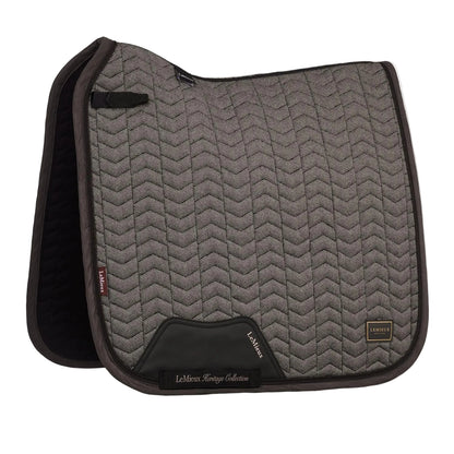 Die braune LeMieux Heritage Dressurschabracke Herringbone Dressage Square in Cocoa zeigt ihr edles Fischgrätmuster in Chevron-Steppung, den anatomischen Schwanenhals-Schnitt für Widerristfreiheit und den verstärkten PU-Leder-Gurtschutz sowie die D-Ring-Befestigung.