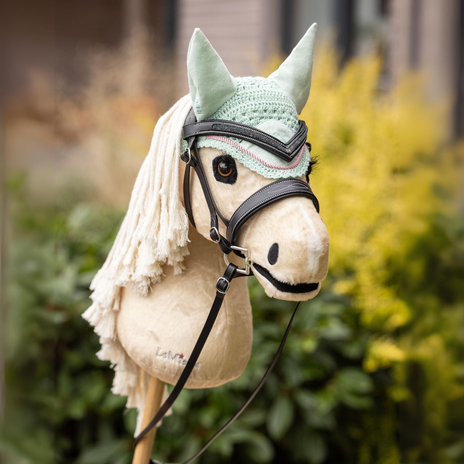 Das LeMieux Hobby Horse Popcorn in Palomino mit brauner LeMieux Hunter Trense und passender Fliegenmütze draußen im Grünen – perfekt ausgerüstet für Training, wilde Ausritte und das nächste Hobby Horsing Turnier.