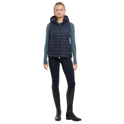 Eine Reiterin im kompletten LeMieux Reitoutfit bereit für den Sattel. Die navy  LeMieux Steppweste Rose wird hier stilvoll kombiniert und zeigt sich als vielseitiges Essential für den Reitsport. Das Bild vermittelt die perfekte Passform und Eleganz der Pufferweste in Aktion am Pferd. Hochwertige Reiterbekleidung für Damen, die Funktionalität im Stall mit einem modernen Look verbindet. Ideal als Inspiration für ein abgestimmtes Outfit im klassischen LeMieux-Stil.