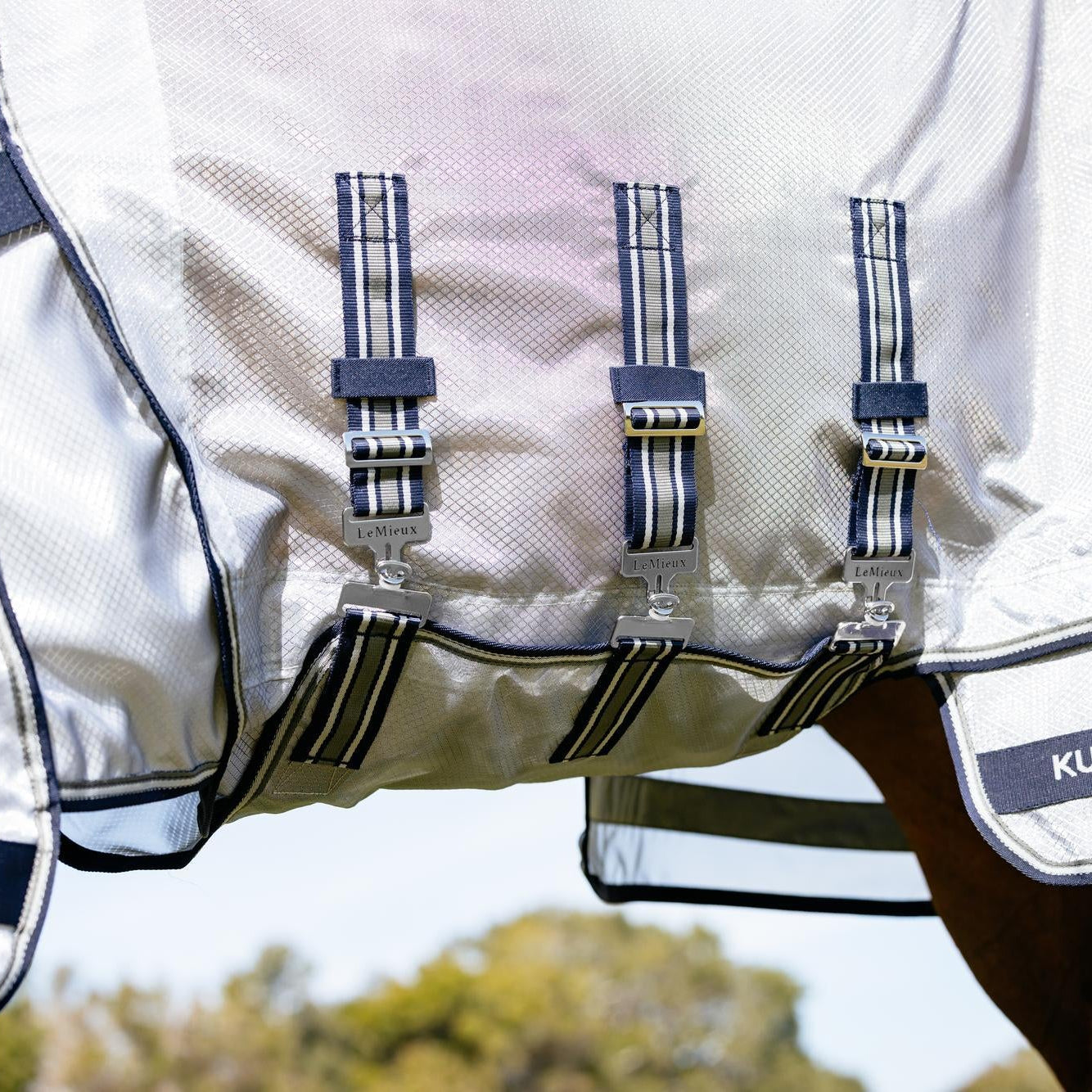 Detailansicht des extra breiten und langen Bauchlatzes der Fliegendecke mit drei geraden Bauchgurten und sicheren T-Verschlüssen, wobei der mittlere Gurt abnehmbar ist. Diese Konstruktion bildet eine undurchdringliche mechanische Barriere an der empfindlichen Bauchnaht des Pferdes und bietet optimalen Schutz vor Kriebelmücken, Bremsen und Fliegen.