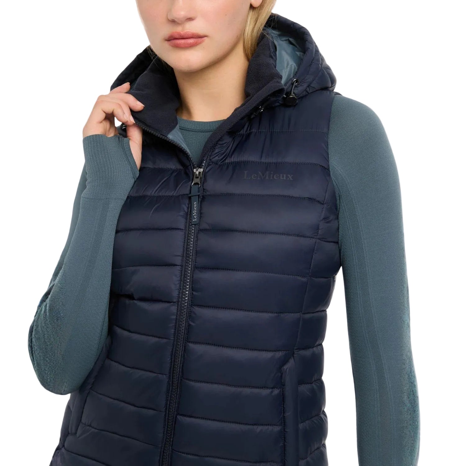 Nahaufnahme der LeMieux Steppweste Rose in Navy mit dem edlen Marken-Branding auf der linken Brust. Die dicke Quersteppung zeigt das hohe Volumen der recycelten Füllung, die für maximale Wärmeisolierung im Stall sorgt. Die zwei praktischen Front-Reißverschlusstaschen bieten sicheren Stauraum für Handy oder Leckerlis beim Reiten. Dank des wasserabweisenden Materials ist diese Damen-Reitweste die ideale Wahl für Reiterinnen, die viel Zeit im Sattel oder draußen verbringen.