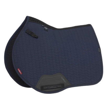 Die LeMieux Schabracke Essence Eurojump Square Navy zeigt ihre anatomische Schwanenhals-Form mit Chevron-Steppung. Der spezifische Eurojump-Schnitt folgt Springsätteln für maximale Schulterfreiheit beim Reiten mit kurzen Steigbügeln. Am Widerrist ist das 3D-Carbon-Mesh Material zu erkennen, während der Gurtbereich durch robustes PU-Leder verstärkt ist und D-Ring Befestigungen besitzt.