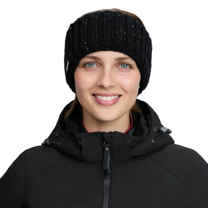 Lächelndes Model präsentiert das schwarze LeMieux Stirnband Bernie als stilvolles Damen-Winteraccessoire. Das breite Strick-Headband mit glitzerndem Paillettengarn schützt die Ohren optimal vor Kälte und ergänzt perfekt ein sportliches schwarzes Reitoutfit.