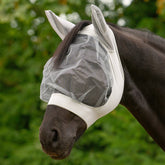 Ein Pferd trägt die silbergraue Waldhausen Fliegenmaske Skinny auf einer grünen Sommerweide. Die elastische Maske sitzt kopfnah und stabil am Pferdekopf, ohne das Tier zu stören. Durch das großzügige Augennetz mit Augenfreiheit genießt das Pferd eine gute Rundumsicht, während der Ohrenschutz mechanisch vor Fliegen und Kriebelmücken schützt.