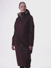 Junge blonde Frau trägt den LeMieux Reitmantel All Elements in der Farbe damson geschlossen und zeigt diesen von vorne, von der Seite und hinten. Am Kragen und der Kapuze ist das beigefarbene Teddy Fleece zu sehen. Der weite lockere Schnitt ist gut zu sehen und auch der Rückseitige Schlitz  der zum Reiten geöffnet werden kann. Das LeMieux Logo auf der linken Brust ist sehr dezent. Die Taschen sind durch Reißverschlüsse alle geschlossen. Der Reitmantel wirkt weit, locker und am Kragen weich und plüschig.