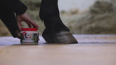 Anwendungsvideo zur optimalen Pferdepflege: Eine Reiterin öffnet den hellen, cremigen leovet Hoof Balm Präbiotisch und zeigt das richtige Auftragen des Hufbalsams mit einem Pinsel. Der präbiotische Balsam wird auf die Hufwand, den Kronrand, die Hufsohle, die weiße Linie und den Strahl aufgetragen, um den gesamten Pferdehuf mit einer pflegenden Schutzbarriere gegen äußere Einflüsse zu umhüllen.