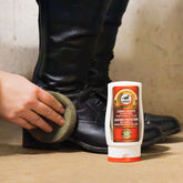 Anwendung des leovet Leder Schutz zur professionellen Reitstiefelreinigung und Lederpflege an einem schwarzen Paar Reitstiefel mittels Schwamm. Das hochwertige Glattleder der Stiefel zeigt nach dem Auftragen einen edlen Glanz und ein gepflegtes Finish, perfekt für den glänzenden Auftritt auf dem Reitturnier.
